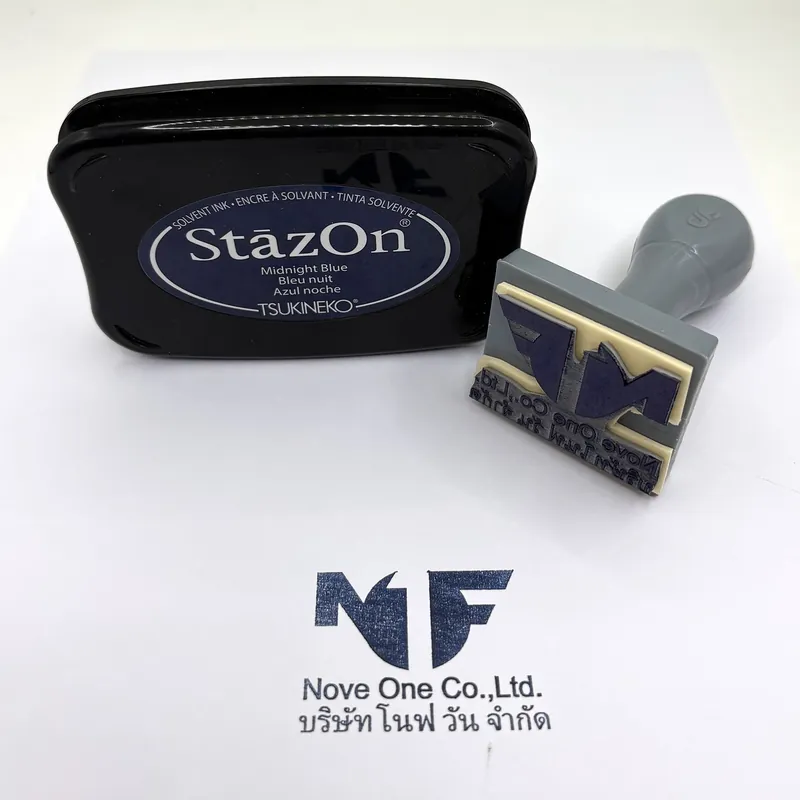 ตรายางโลโก้บริษัทพร้อมชื่อบริษัทไทยและอังกฤษ วางข้างแท่นหมึก StazOn